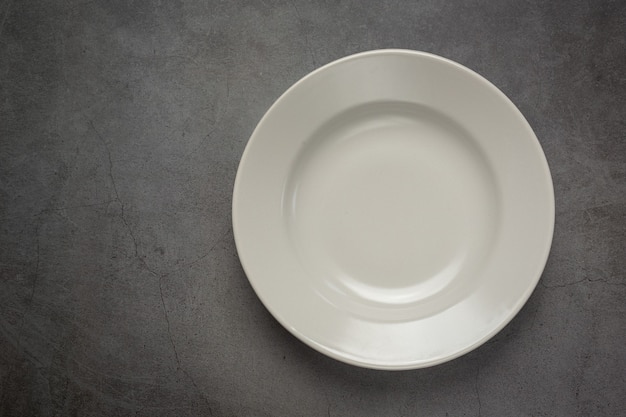 A white round empty  plate on dark surface Free Photo