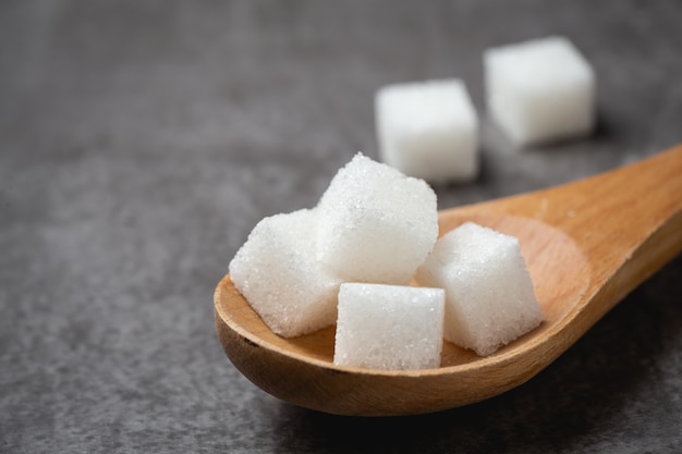 White sugar cube in wood spoon on table. Free Photo