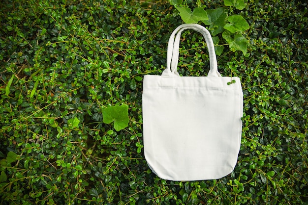 White tote canvas fabric eco bag cloth shopping sack on green leaf nature background Premium Photo