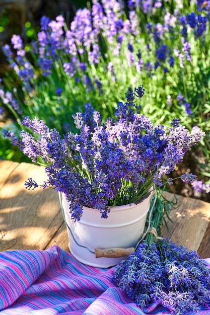 ラベンダー畑の背景に 木製のテーブルにラベンダーの花束と白い花瓶 プレミアム写真