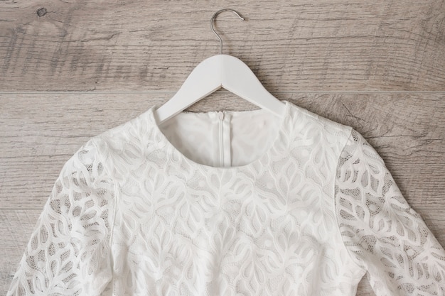 White Wedding Dress On Coat Hanger Against Wooden Textured