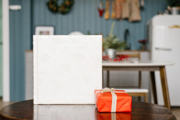 Premium Photo White Wedding Photo Book With A Leather Cover With Lace And A Red Christmas Gift Box On The Table