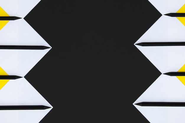 White and yellow stickers with black pencils lined with a geometric pattern on a black background. Premium Photo