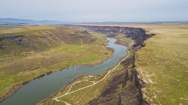 Wide shot of a river flowing among green hills under a clear sky | Free ...