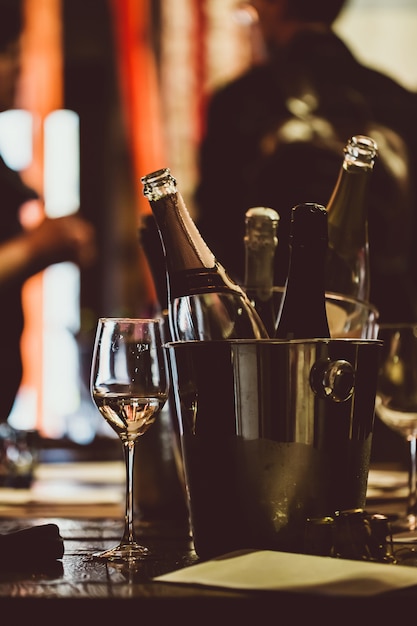 Wine tasting: on a wooden table there is a silver bucket for cooling wines with open bottles. Premium Photo