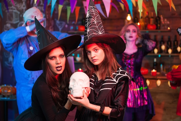 Premium Photo | Witches with serious face holding a human skull at ...