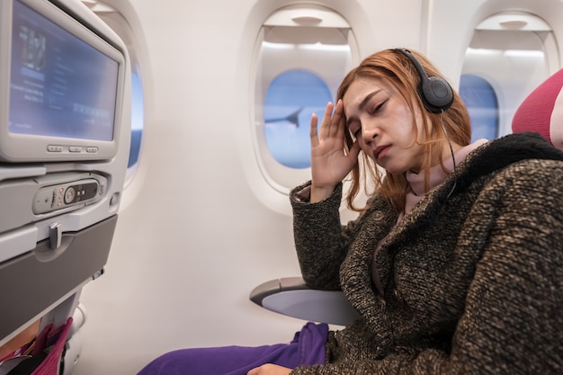 Woman in airplane suffer from airsick with stress headache in flight time. Premium Photo