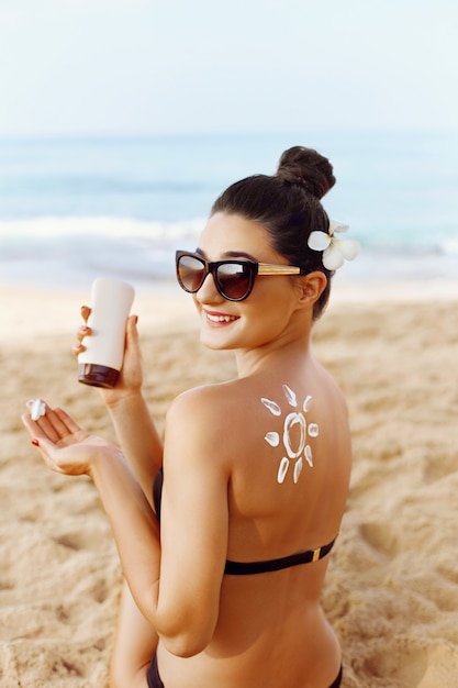 Premium Photo Woman Applying Sun Cream On Tanned Shoulder In Form Of