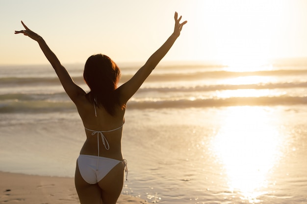 Woman in bikini standing with arms up on the beach Free Photo