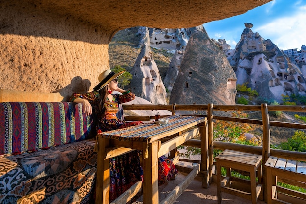 Woman in bohemian dress sitting on traditional cave house in cappadocia, turkey. Free Photo