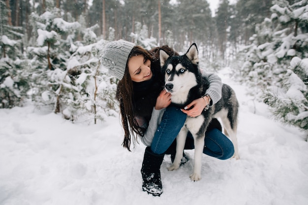 無料の写真 冬の雪の寒い日にハスキー犬を愛撫する女性