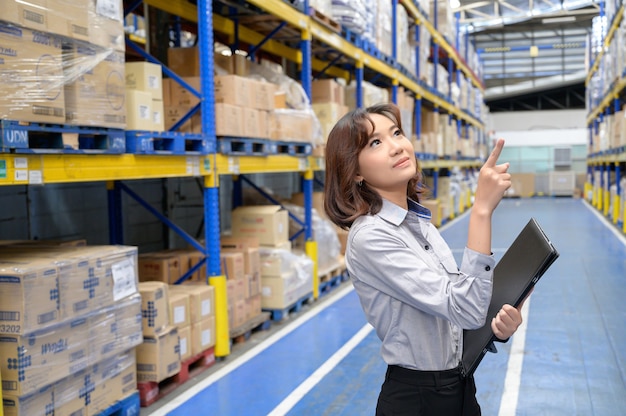 Woman checking and counting the products in the shelf at the big storage and warehouse Premium Photo