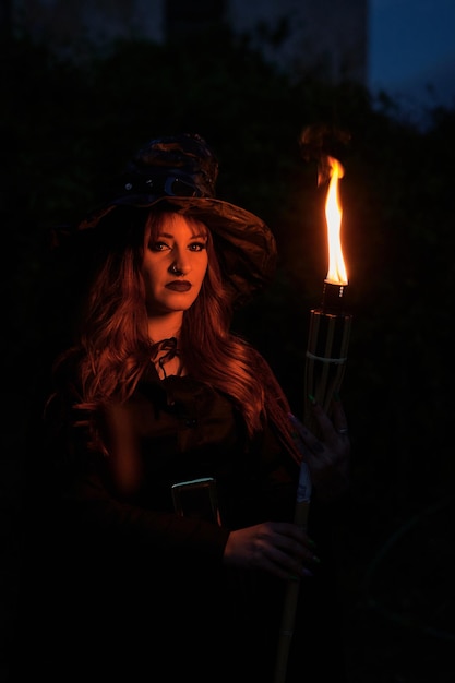 Premium Photo | Woman disguised as a witch holding a flaming torch