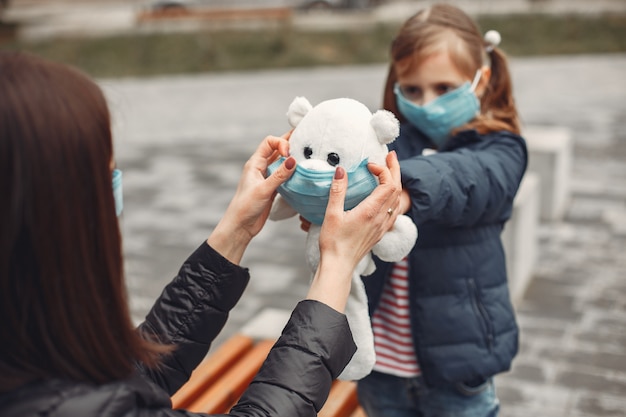 Woman in a disposable mask is teaching her child to wear a respirator Free Photo