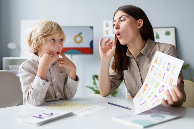 Woman doing speech therapy with a little blonde boy Free Photo