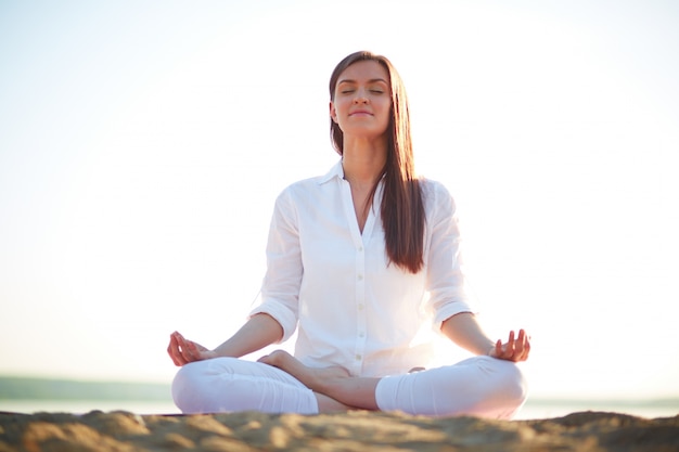 Woman doing yoga exercises on the beach Free Photo