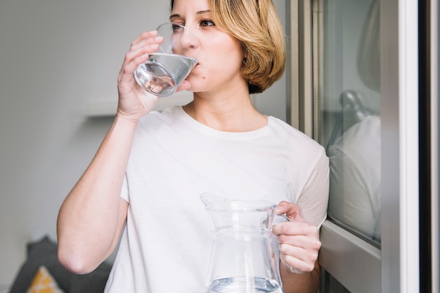Woman drinking water near window Free Photo