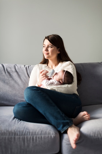 Woman feeding baby with bottle | Free Photo