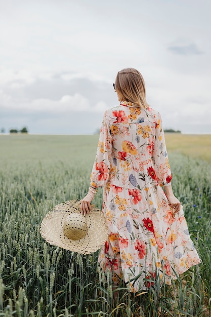 Premium Photo | Woman in a floral dress with a woven hat in a field