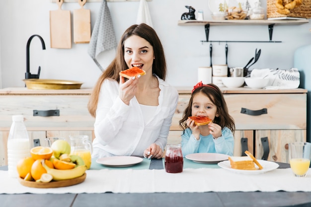 Woman and girl having breakfast at the kitchen Free Photo