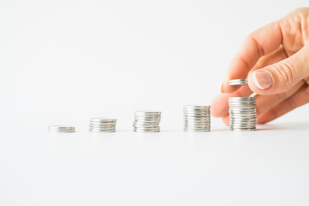 Woman hand adding coins to pile Free Photo