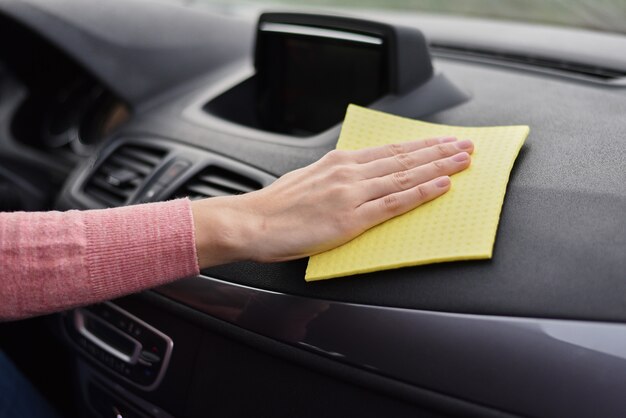 女性の手が黄色のマイクロファイバータオルで車のダッシュボードを掃除します クリーニング車のコンセプト プレミアム写真