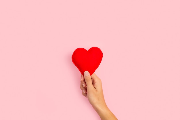 Premium Photo | Woman hand holding a fabric red heart on a pink ...