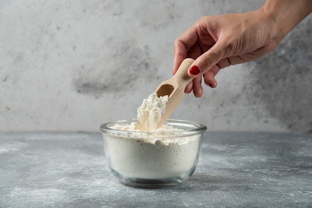 Woman hand holding spoon on top of flour bowl. Free Photo