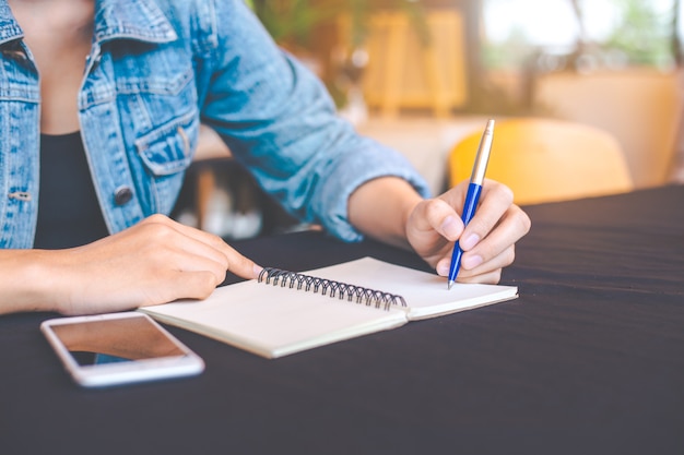 Premium Photo | Woman hand is writing on a note pad with a pen in the ...