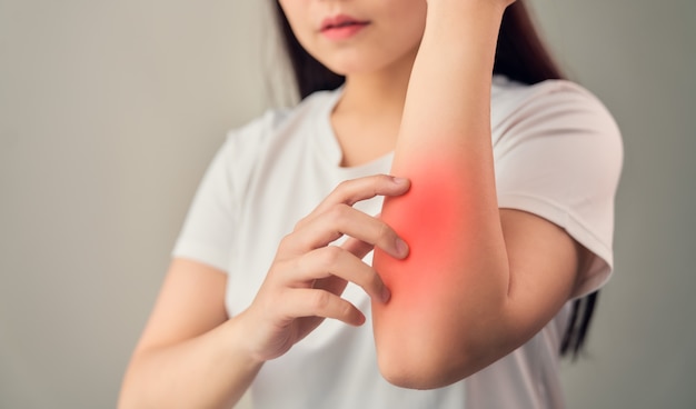 Woman hand touching elbow from chronic joint rheumatism and there is so much suffering. on the gray background. Premium Photo