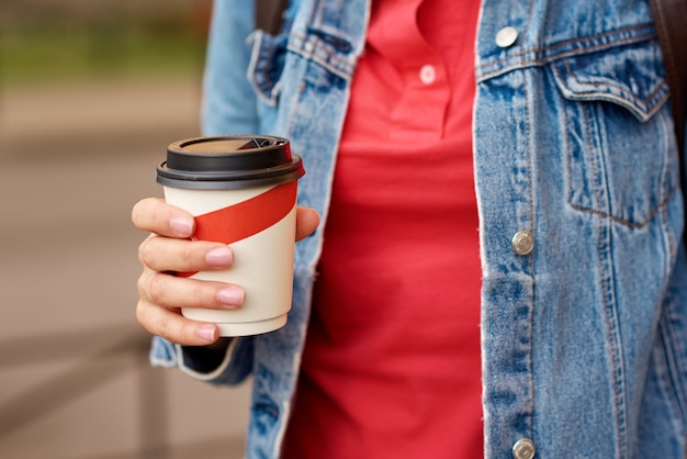 コーヒーの紙コップを持つ女性の手が街で奪う プレミアム写真