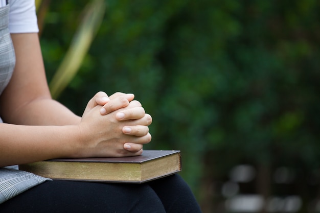 Premium Photo | Woman hands folded in prayer on a holy bible for faith ...