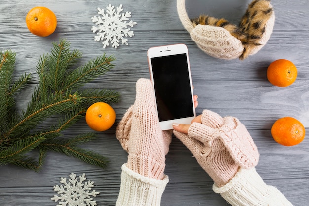 Free Photo Woman Hands In Mittens With Smartphone Near Fir Branches And Paper Snowflakes