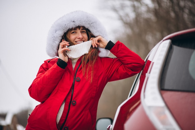 Woman happy talking on the phone outside by car in winter Free Photo