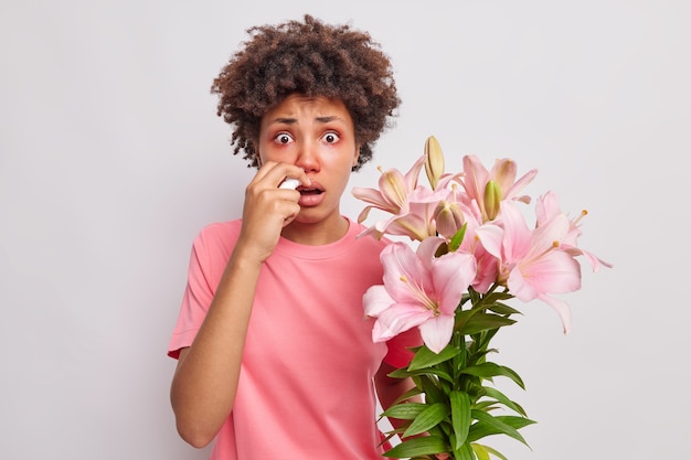 女性はユリにアレルギーがあり 鼻水やその他の不快な症状に苦しんでいます 点鼻薬を使用します くしゃみは常に白で屋内でポーズをとります 無料の写真