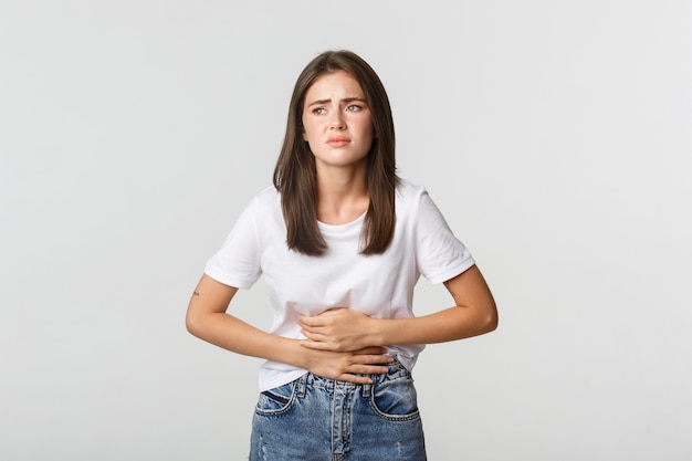Woman having stomach ache, bending and holding hands on belly