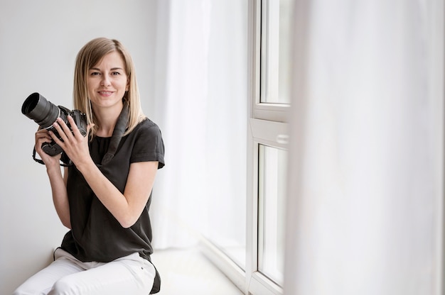 Woman holding a camera and sitting on window sill Premium Photo