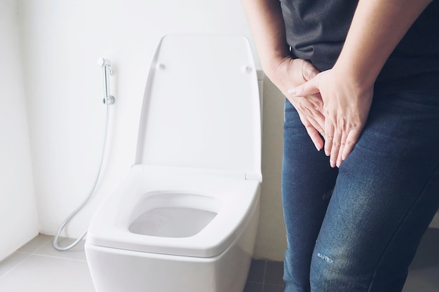 Woman holding hand near toilet bowl - health problem concept Free Photo