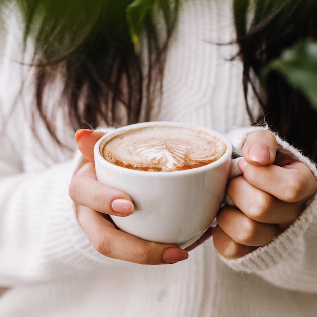 Free Photo | Woman holding hot coffee cup in white knitted jacket