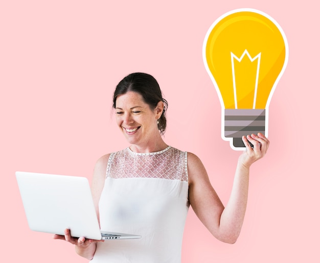 Woman holding an idea icon and using a laptop Free Photo