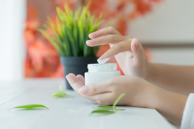 Woman holds a jar with a cosmetic cream in her hands Free Photo