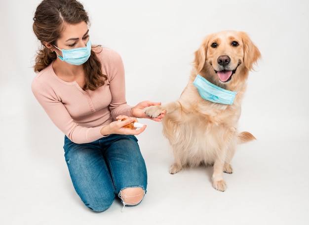 医療用保護マスクの女性が犬の足を消毒剤で消毒 プレミアム写真