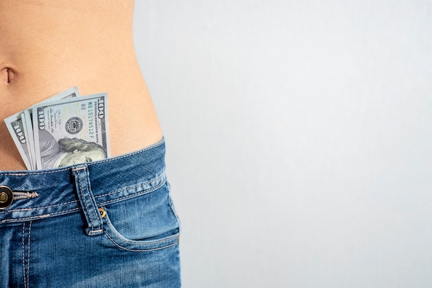 Premium Photo | A woman in jeans with a bare stomach with dollars ...