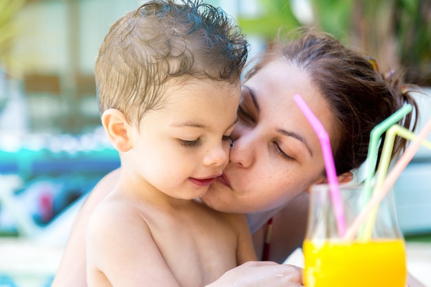 子供とフルーツジュースのガラスにキスをする女性 プレミアム写真