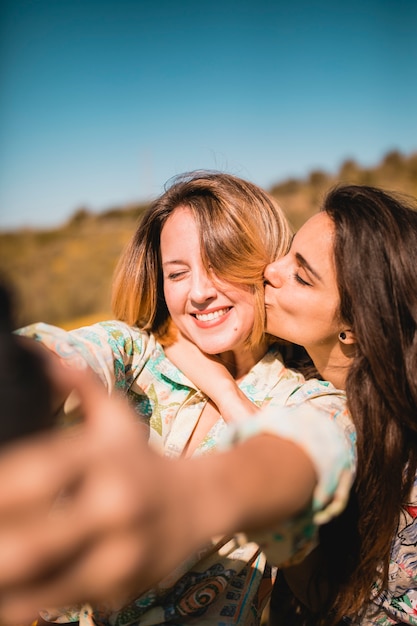 woman kissing friend and taking. 