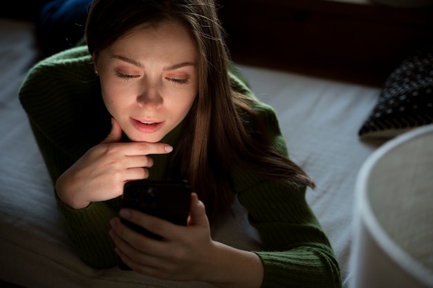 Free Photo Woman Laying On The Bed While Looking At Her Smartphone