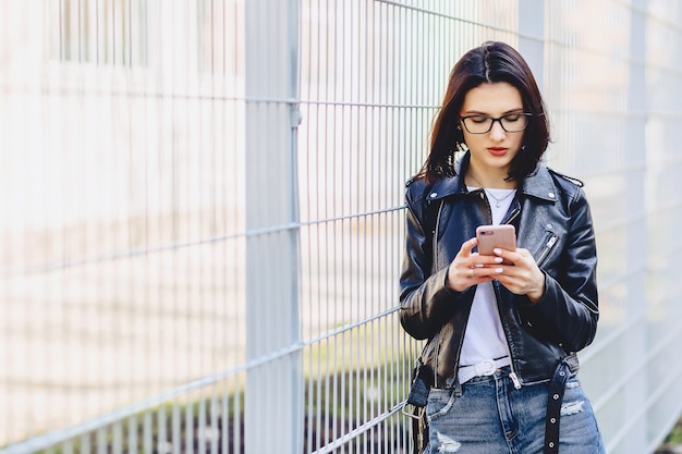 Woman in leather jacket messaging on phone at street Premium Photo
