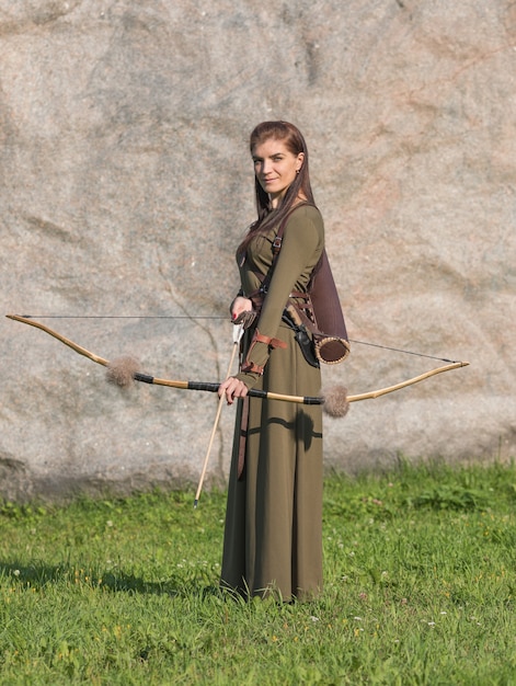 Premium Photo | Woman in long dress holding bow and arrow