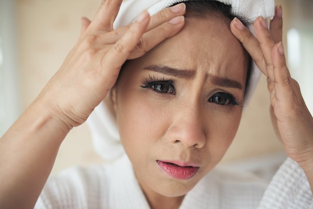 woman looking at mirror at home and checking her face Free Photo