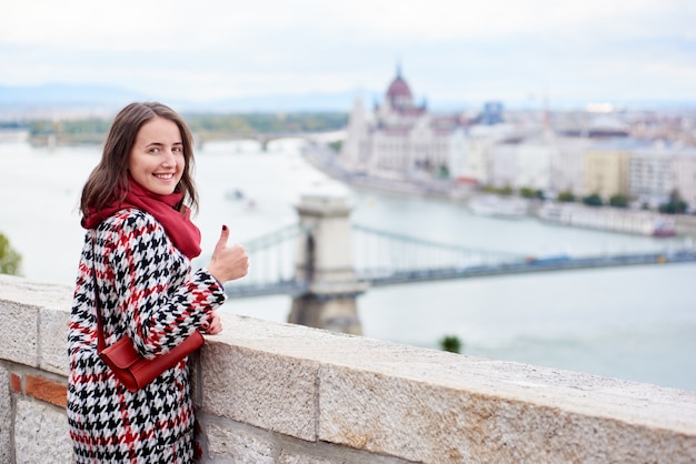 https://image.freepik.com/free-photo/woman-looking-back-camera-with-smile-showing-thumb-up-gesture-good-class-against-beautiful-view-hungarian-parliament-chain-bridge-budapest-hungary_10069-3832.jpg